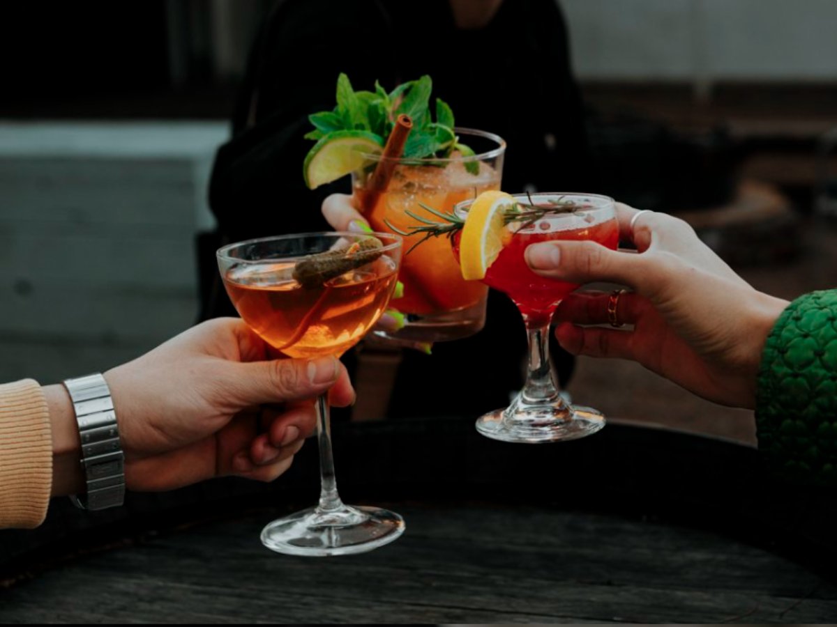 Closeup of 3 hands holding fancy drinks and doing cheers for article Sensational Desert Nightlife in Tucson for newcomers moving to Tucson.