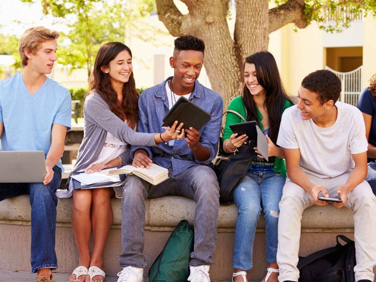 A group of high school students sitting outside with papers and ipads for article 3 Tucson-area Schools Ranked among Best in the Nation for newcomers moving to Tucson.
