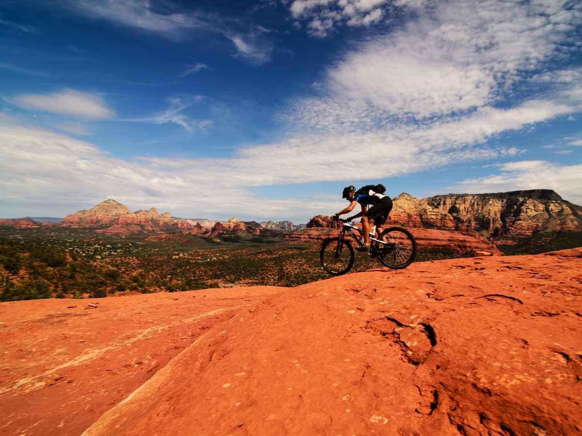 Person riding bike with the desert mountains of Arizona in the background for article Best Desert Cycling in Tucson for newcomers moving to Tucson.