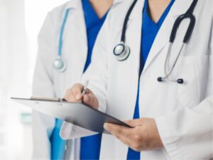 Close up of 2 doctors with stethoscopes around neck and white jackets. One of the doctors is holding a chart and writing on it for article Top Doctors in Tucson for newcomers moving to Tucson.