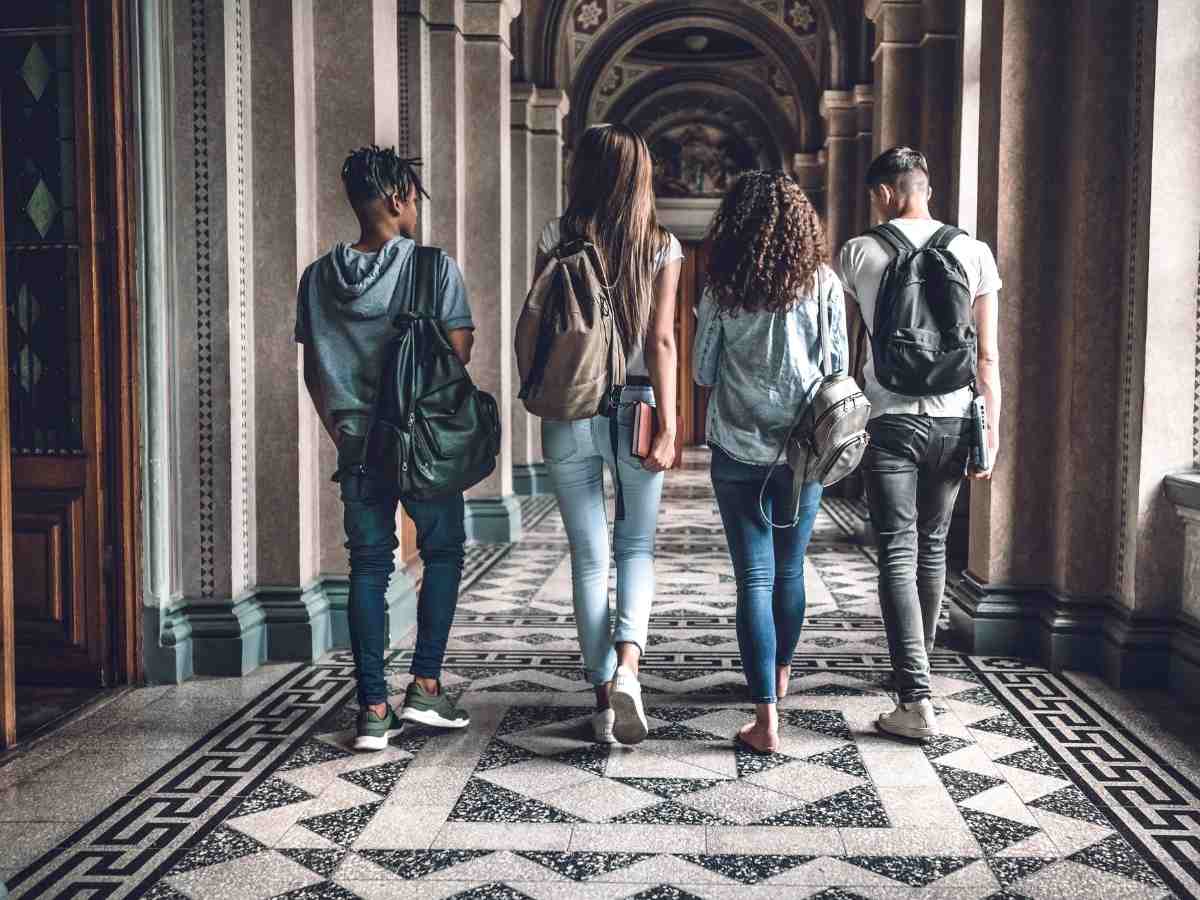 4 College students walking down large university hallway away from camera for article 15 Popular Arizona Higher Education Opportunities for newcomers moving to Arizona.