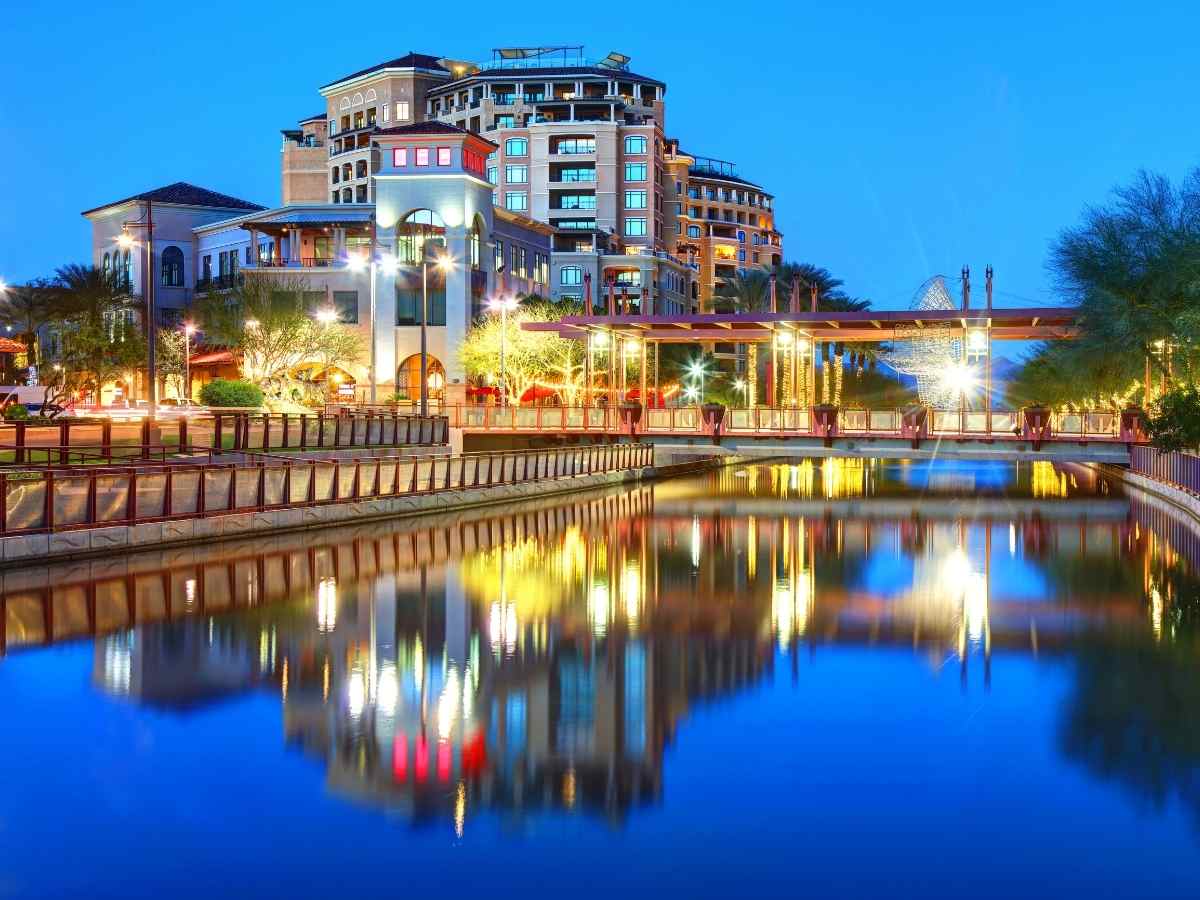 Large building in Scottsdale being reflected in water at dusk for article Living in Scottsdale: Why Old Town Is a Top Choice for Newcomers moving to Arizona.