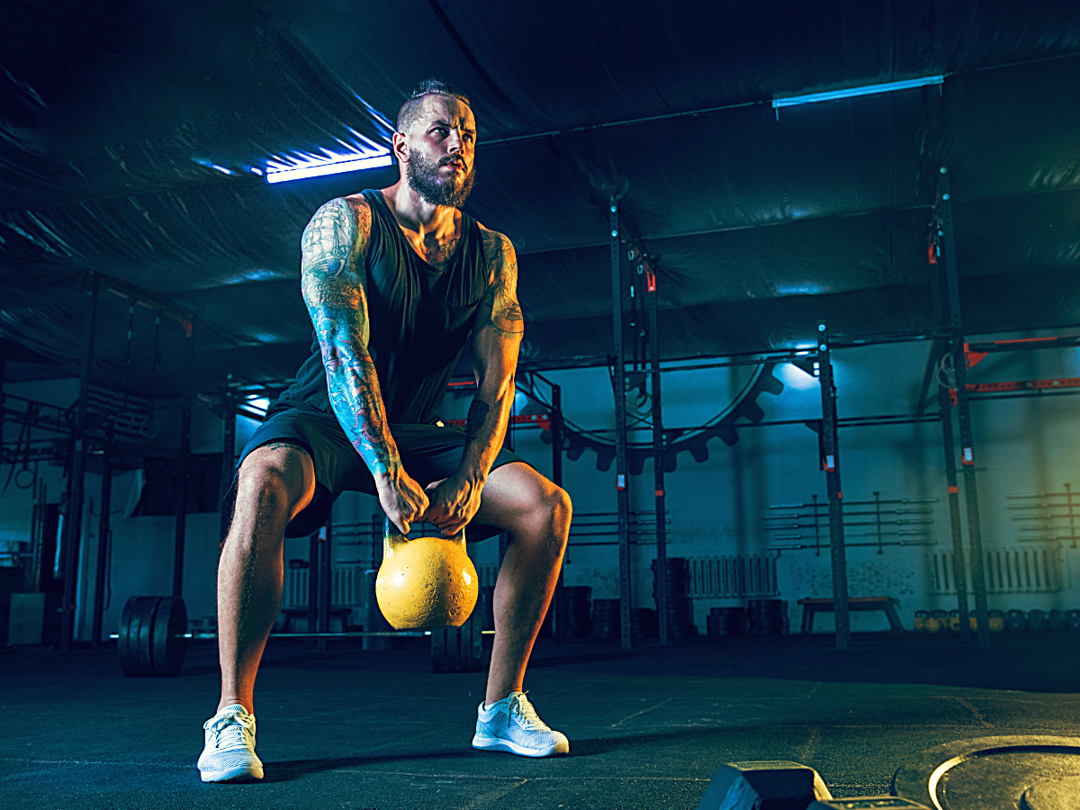 Male lifting kettlebell in crossfit gym.