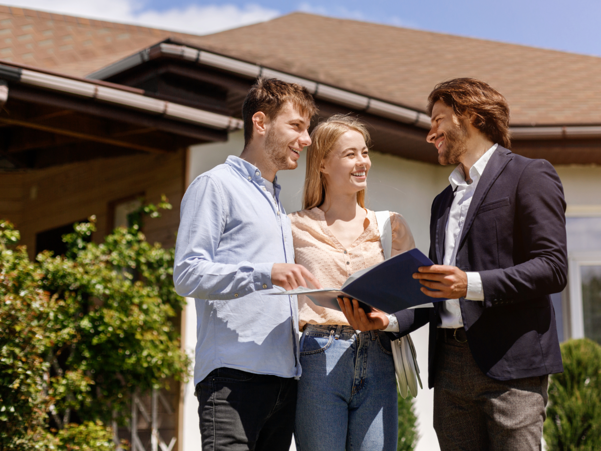 Realtor showing a couple a home - standing outside the home.