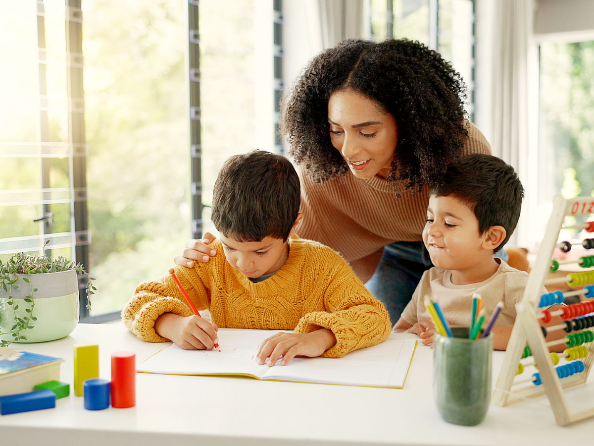 Mom homeschooling 2 boys at kitchen table.