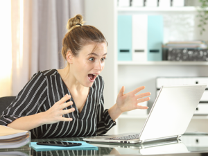 Person celebrating in front of computer after finding contract work online.