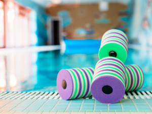 Pools foam hand dumbell weights sitting on edge of pool.