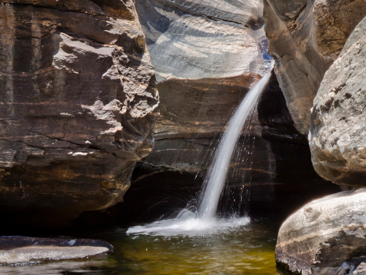 Waterfall coming through rock into cavern pool off mountainside for article 5 Unforgettable Outdoor Adventures in Tucson for Newcomers moving to Tucson.