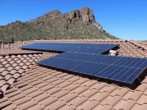 Close up of roof of house with solar panels on it and Mountains in background for article Sustainable Living in Tucson in 2025 for newcomers moving to Tucson.
